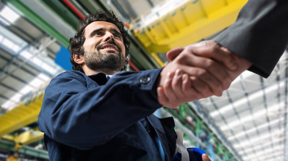 Portrait of a man giving an handshake in an industrial facility | Jobless Rates Go Down In States That Removed Extra Benefits | featured
