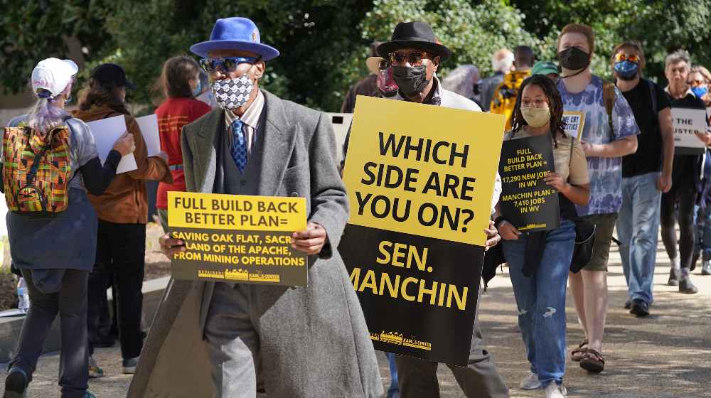 Protesters at the Hart Senate Office Building carry signs calling for Sen. Manchin to support the full Build Back Better Bill | Manchin Won’t Support Democrat’s $2T Build Back Better Program | featured