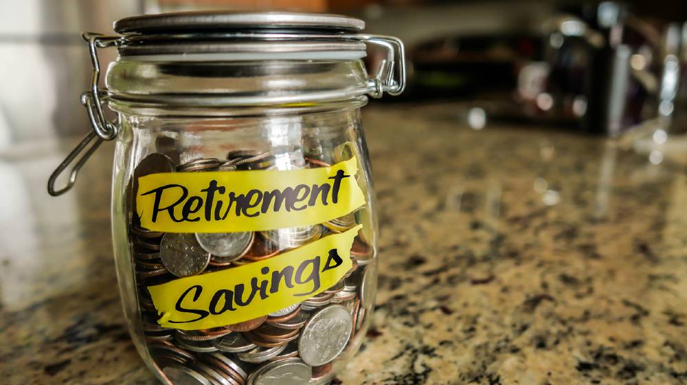 Retirement Savings Money Jar. A clear glass jar filed with coins and bills | 7 Tips to Help You Boost Your Retirement Savings | featured