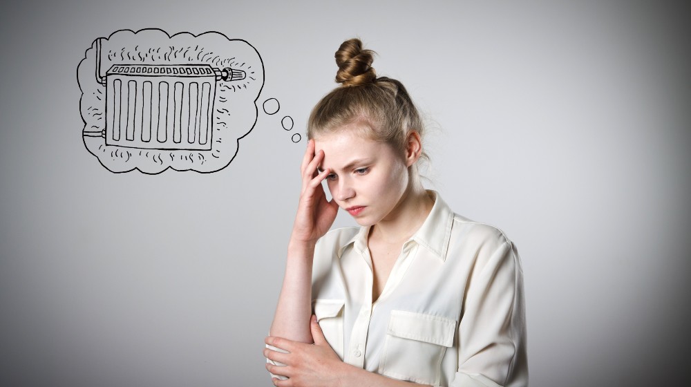 Sad young woman in white and heating season. Heating season, taxes and saving concept | This Winter, Expect Your Heating Bills To Rise By 50% | featured