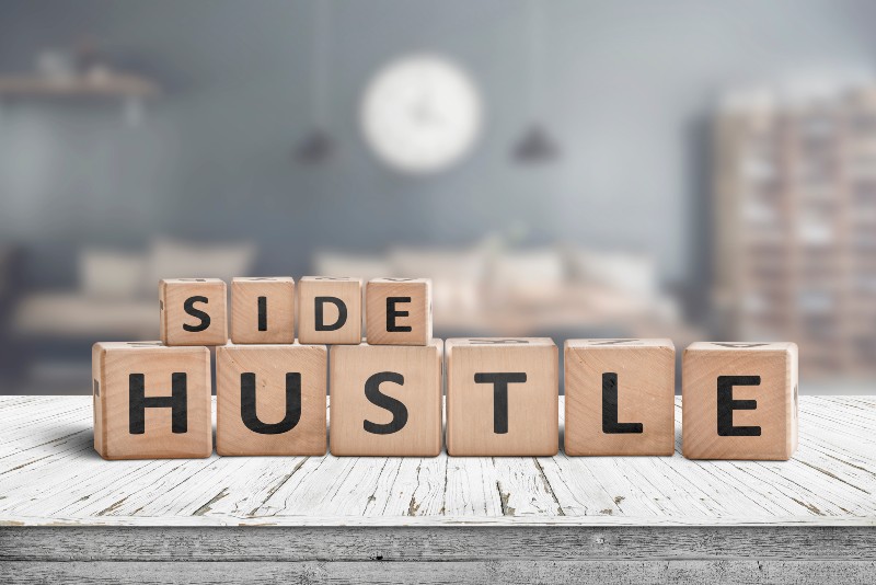 Side hustle sign on a plank table in a decorative room with a clock-Side hustle