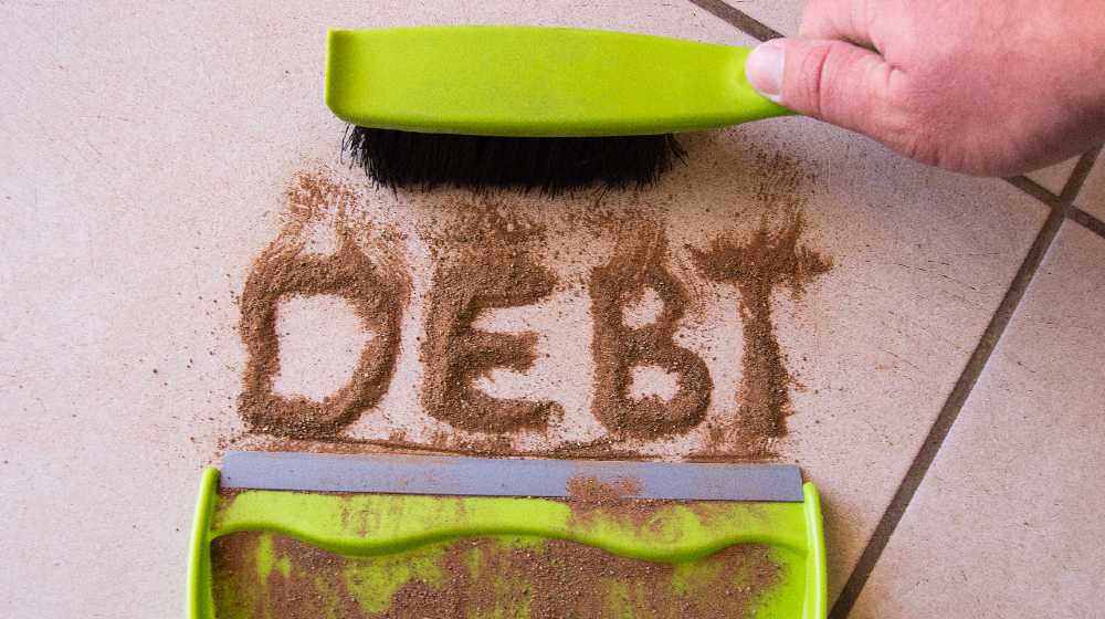 Sweep debt clean concept with debt written in dirt on a floor and a person is about to sweep the debt dirt | How To Get Out of Debt Without Losing Time and Money | featured