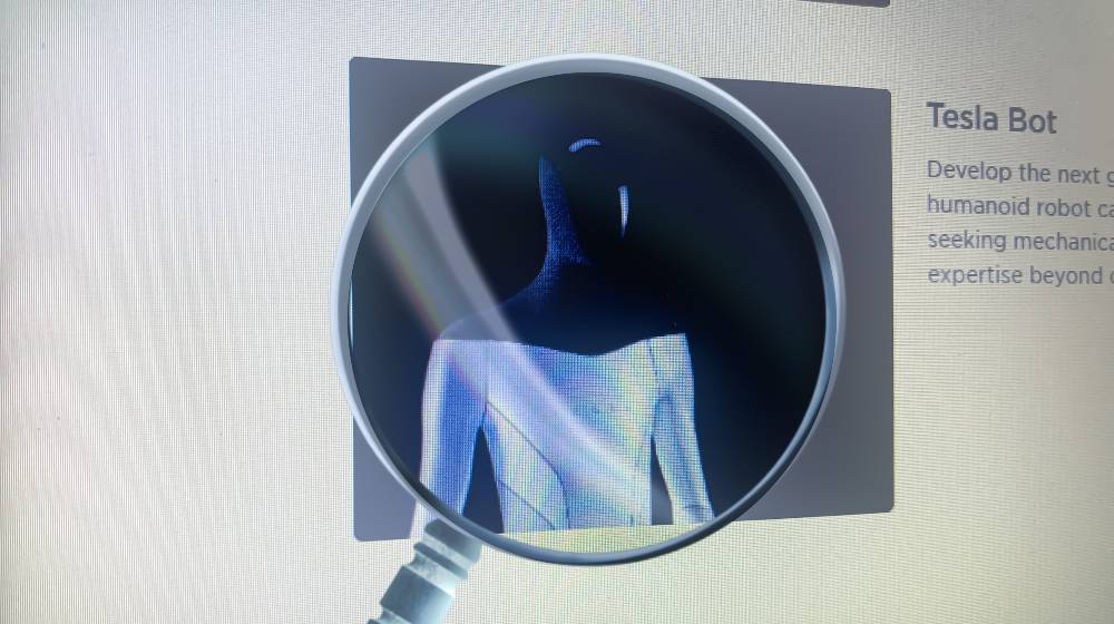 Tesla Bot - Humanoid Robot on laptop screen seen through an optical prism | Elon Musk Unveils Tesla Bot Designed For Boring Work | featured