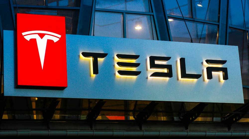 Tesla sign on the building on car sales | Tesla Joins $1 Trillion Dollar Market Cap Club | featured