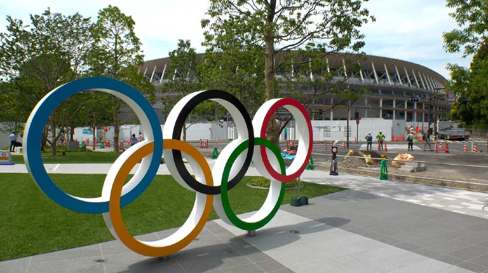 The five ring symbol of the Olympic Games and view of the New National Stadium under construction for Tokyo Olympic 2020 | US Issues Travel Warning to Japan Despite Tokyo Olympics | Featured