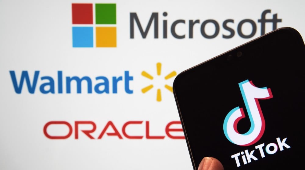 TikTok logo on the mobile screen and blurred logos of Microsoft, Walmart, Oracle on the blurred display on the back-TikTok Oracle-ss-featured