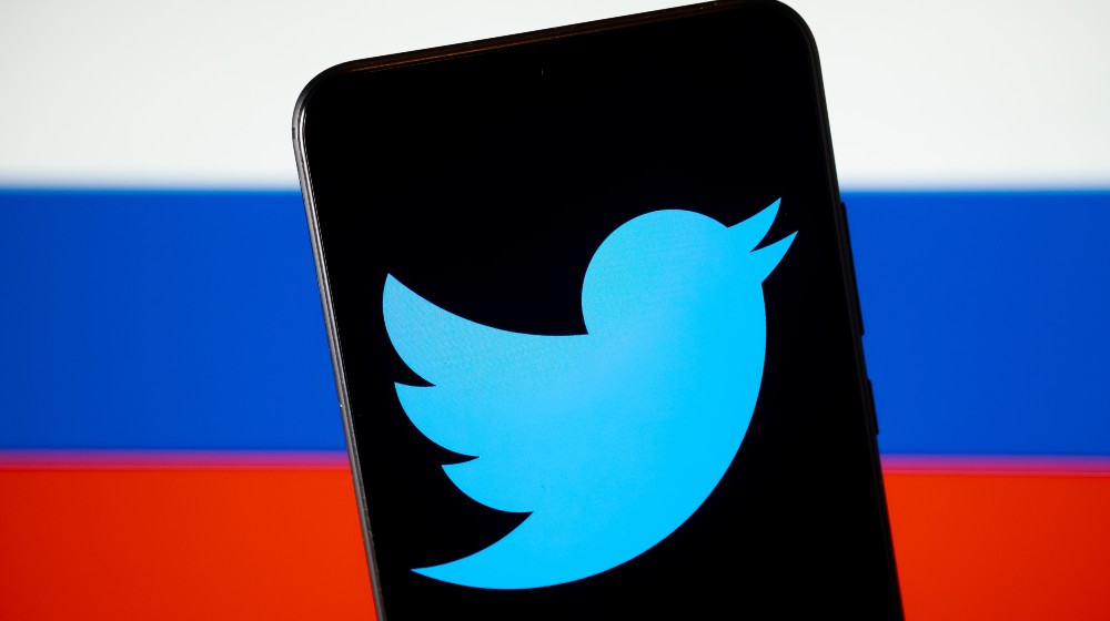 Twitter logo seen on the smartphone screen and blurred flag of Russia on the back | US Tech Firms Under Pressure To Take Hard Stance On Russia | featured