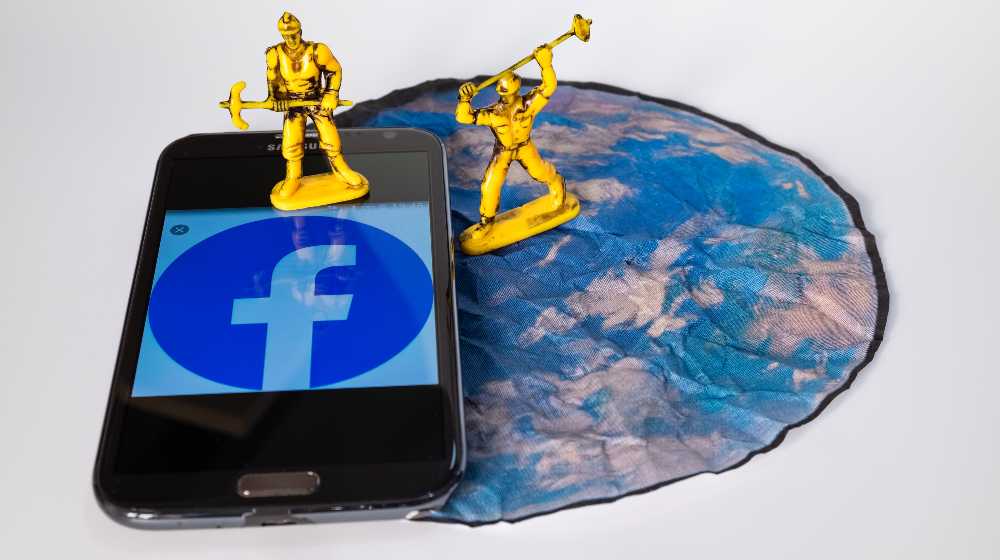 Two toy workers simulate the destruction of the Social Network Facebook on a smartphone | Upcoming Facebook Rebrand Includes Changing Its Name | featured