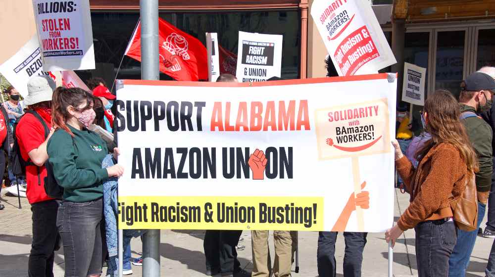 Unidentified participants protesting Amazon's treatment of employees and their attempts to bust up formation of a union for workers | Amazon Workers In Alabama To Vote Again For A Union | featured