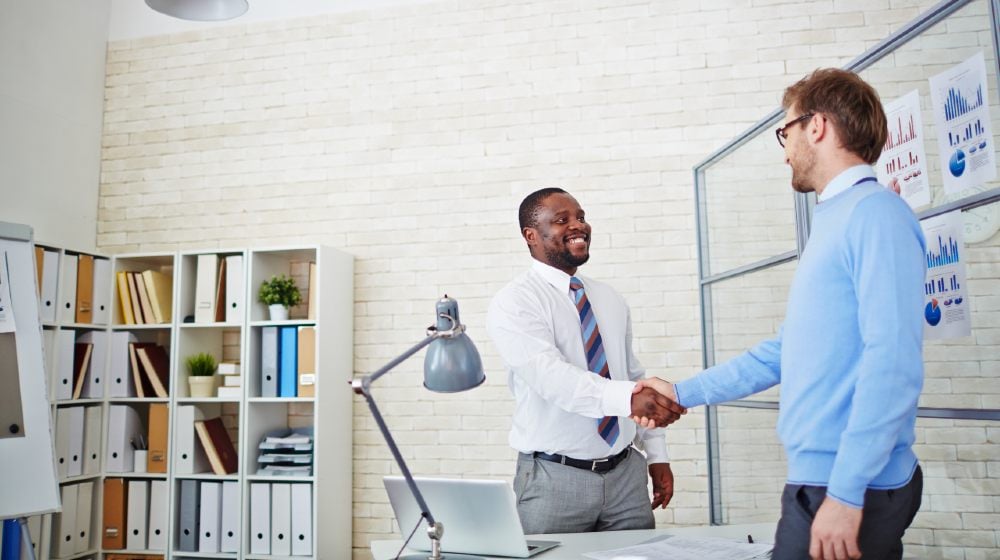 Young employer congratulating newly hired man | 9 critical strategies to attract and retain new workers | Featured