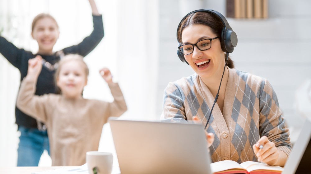 Young mother with children working on the computer. Family at home. Remote work | Firms Realize Remote Work Isn’t Going Away Soon | featured