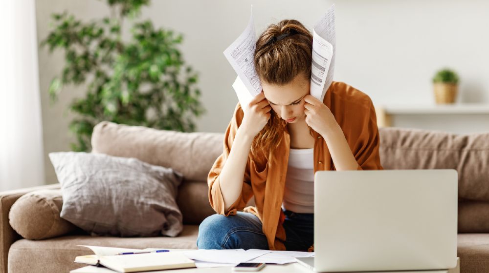 Young tired freelancer in casual clothes focusing on papers and searching for problem solution | Top 10 Startup Mistakes | featured