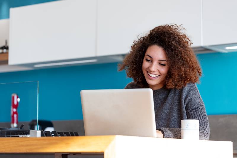 Young woman working remotely from her home kitchen-WFH Employees