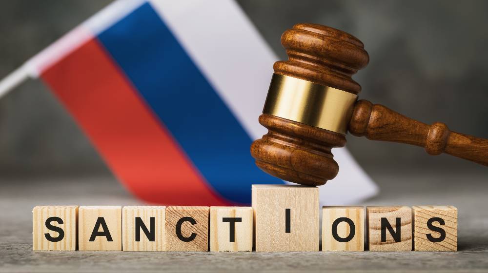 judge's gavel, wooden cubes with the text on the background of the Russian flag | Will Economic Sanctions Work Against Russia This Time? | featured